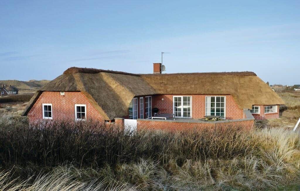 Rotes Backsteingebäude mit strohgedecktem Dach und Fenstern im Freien