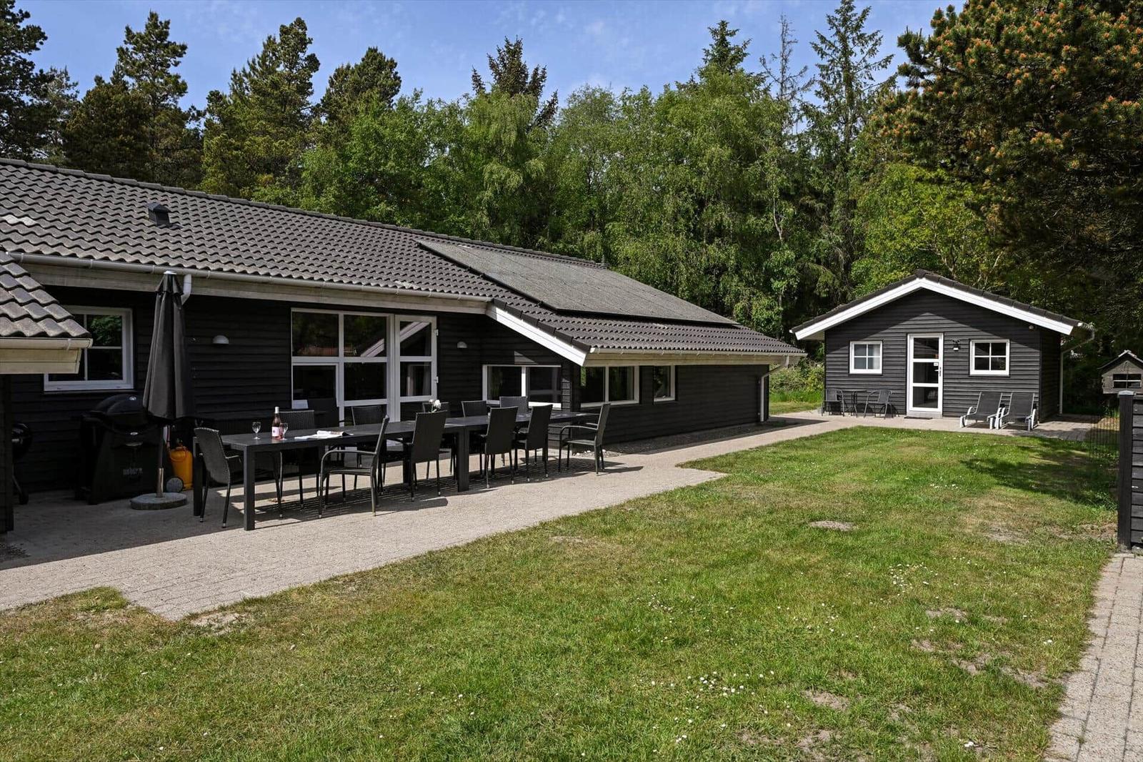 Schwarze Ferienhaus mit Terrasse, Garten und Grillplatz. Hinterhof mit kleinem Haus.