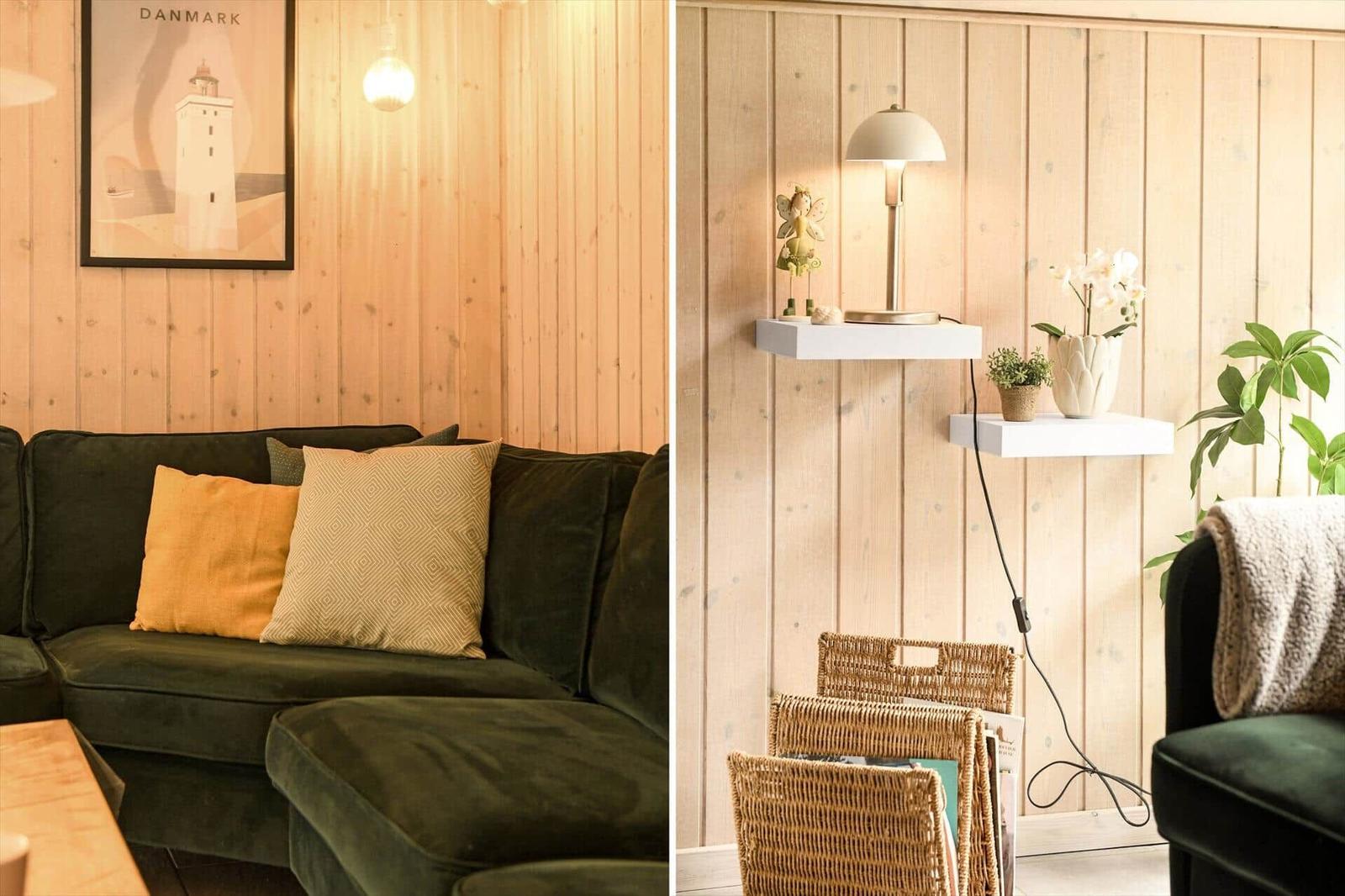Ein Wohnbereich mit grünem Sofa, Kissen und Holzwand. Regale mit Pflanzen und Lampe.