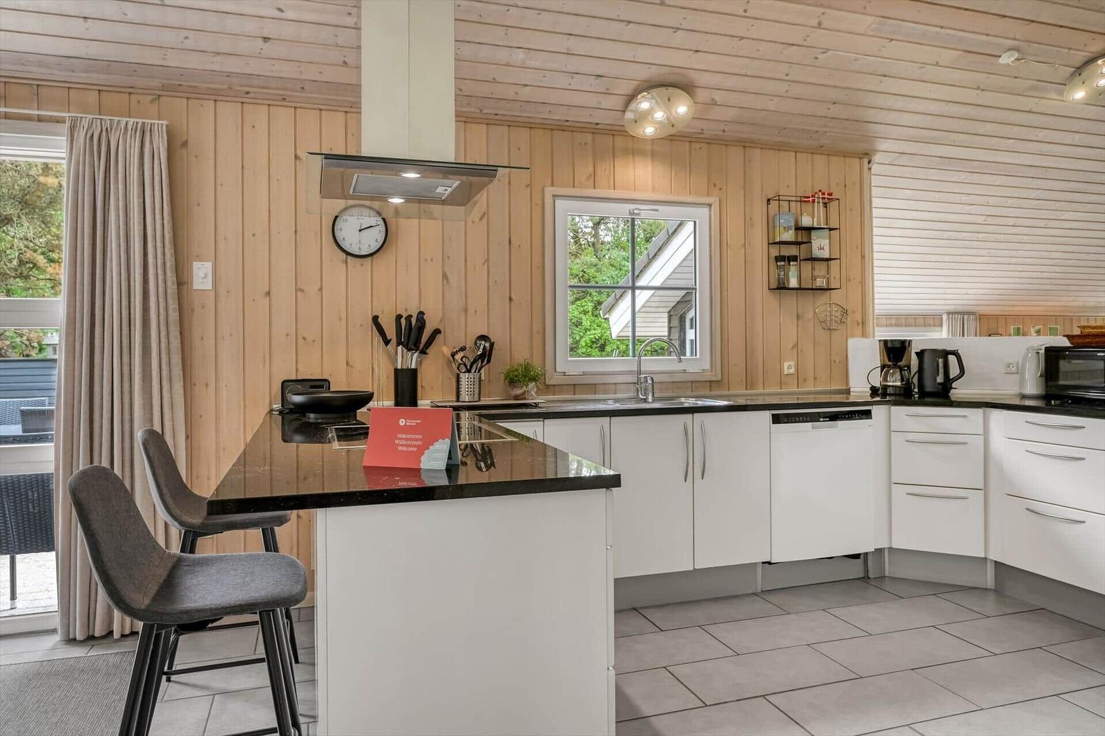 Moderne Küche mit Holzwand, weißer Arbeitsplatte und Kücheninsel mit Barhockern.