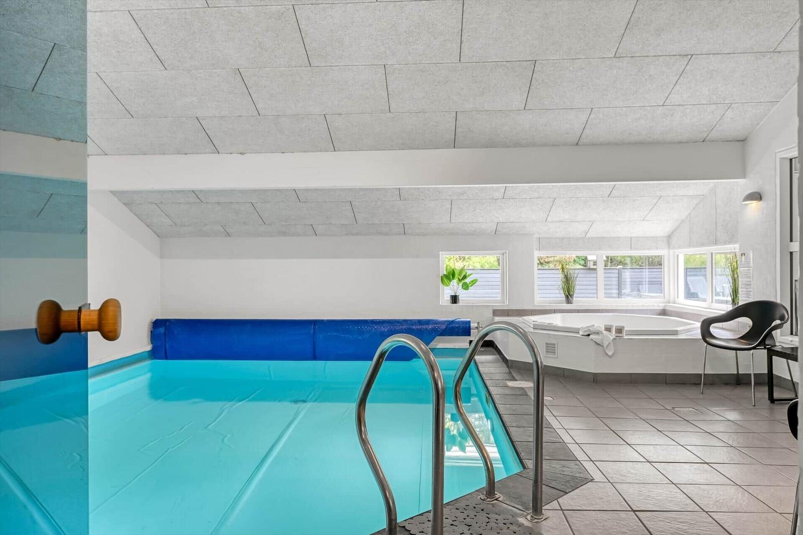 Indoorpool mit Dusche und Whirlpool. Fenster bieten Tageslicht.
