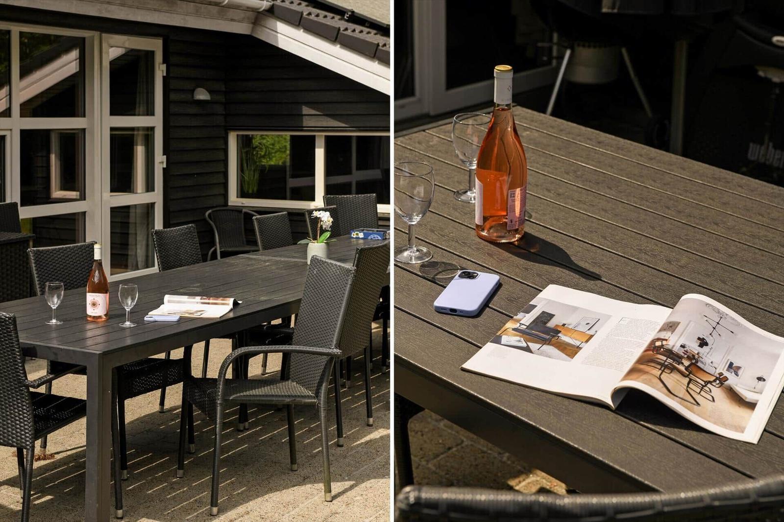 Terrasse mit Tisch, Stühlen, Weinflasche und Zeitschrift.