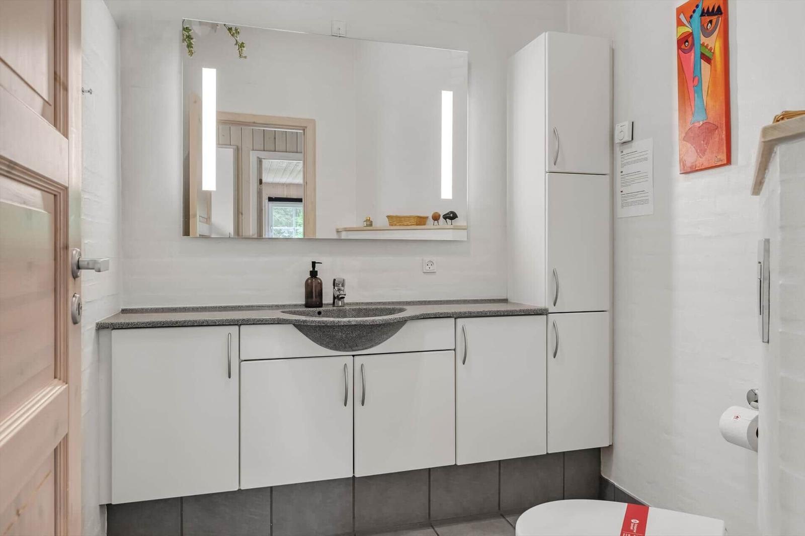 Badezimmer mit Spiegelschrank, Waschbecken und Toilette.