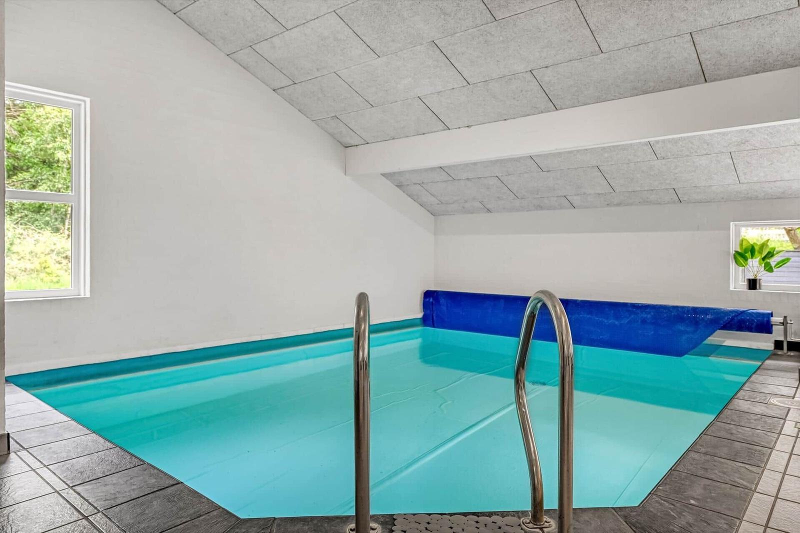 Innere Schwimmhalle mit blauem Becken und Metalltreppe