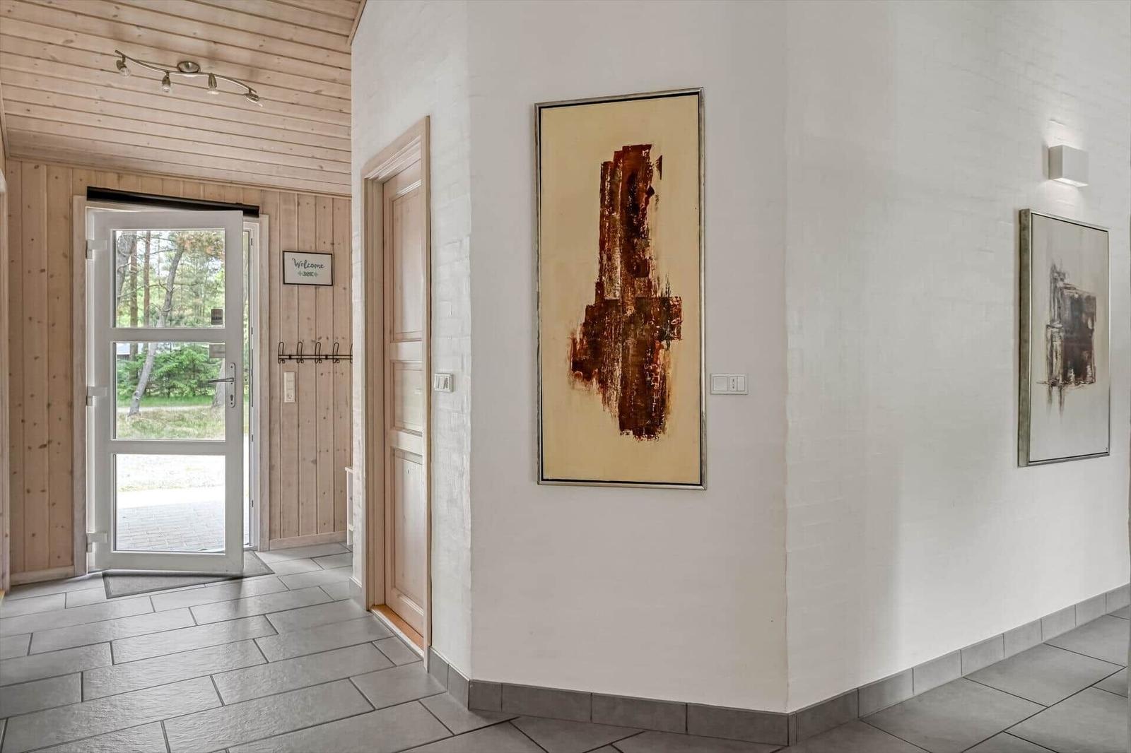 Halle mit Holzwand, Tür zum Außenbereich und Wandbildern.