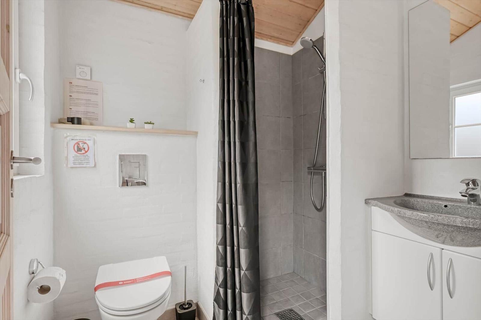 Badezimmer mit Dusche, Toilette und Waschbecken.