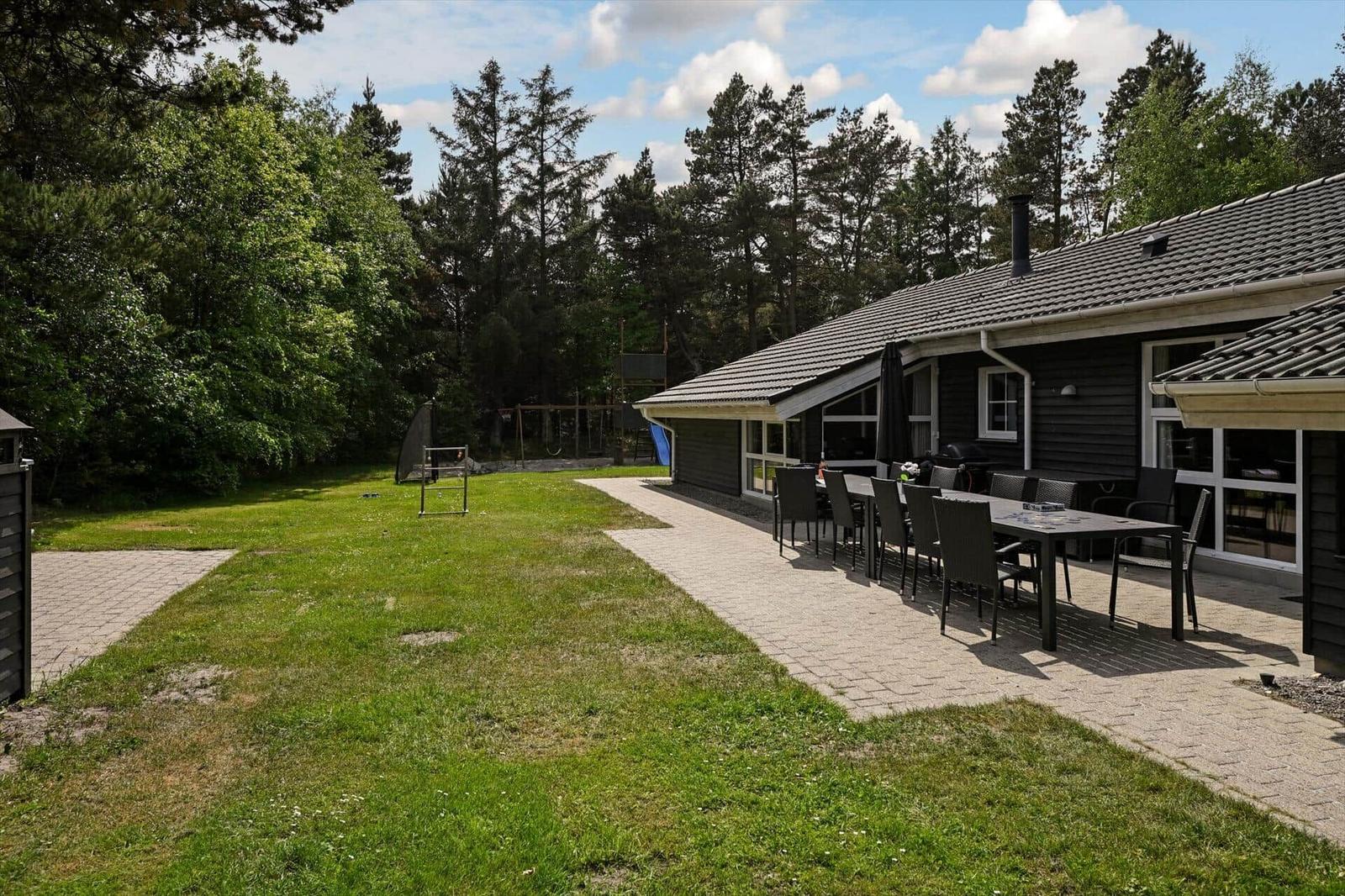 Haus mit Terrasse, Garten und Grillplatz im Wald.