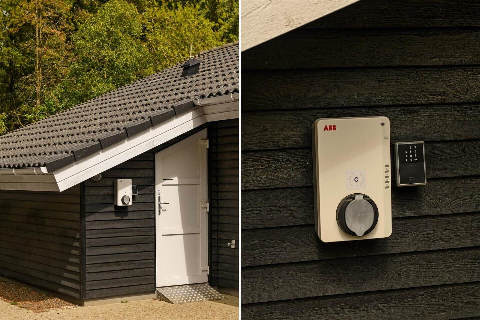 Haus mit dunkler Holzfassade, weißer Tür und elektronischem Türöffner an der Wand.