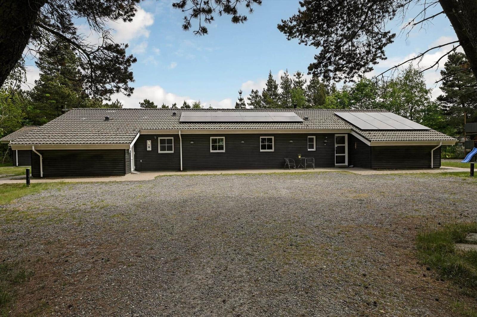Schwarzes Haus mit Solaranlage und Garten. Außenbereich mit Tisch und Stühlen.
