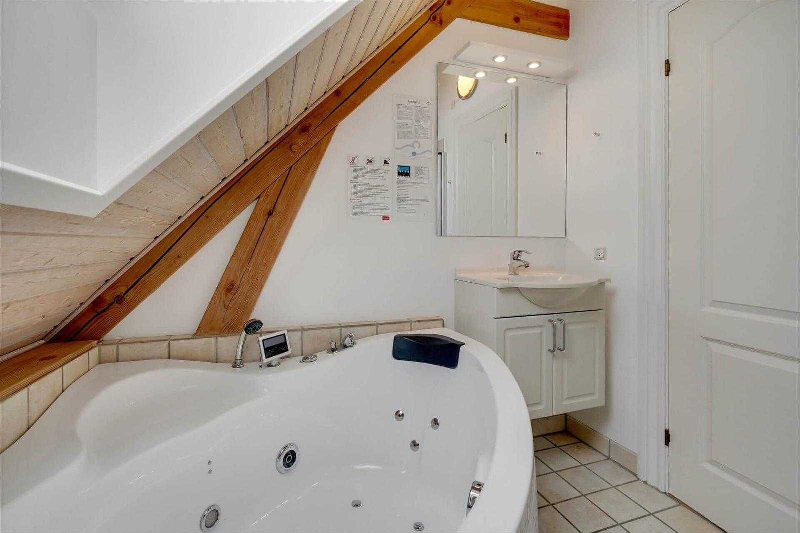Bad mit Whirlpool, Holzbalken, Waschbecken und Spiegel