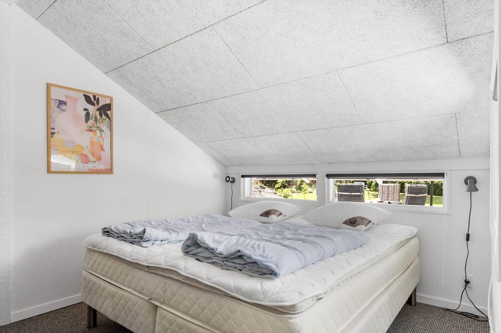 Schlafzimmer mit Bett, Fenstern und Wandbild