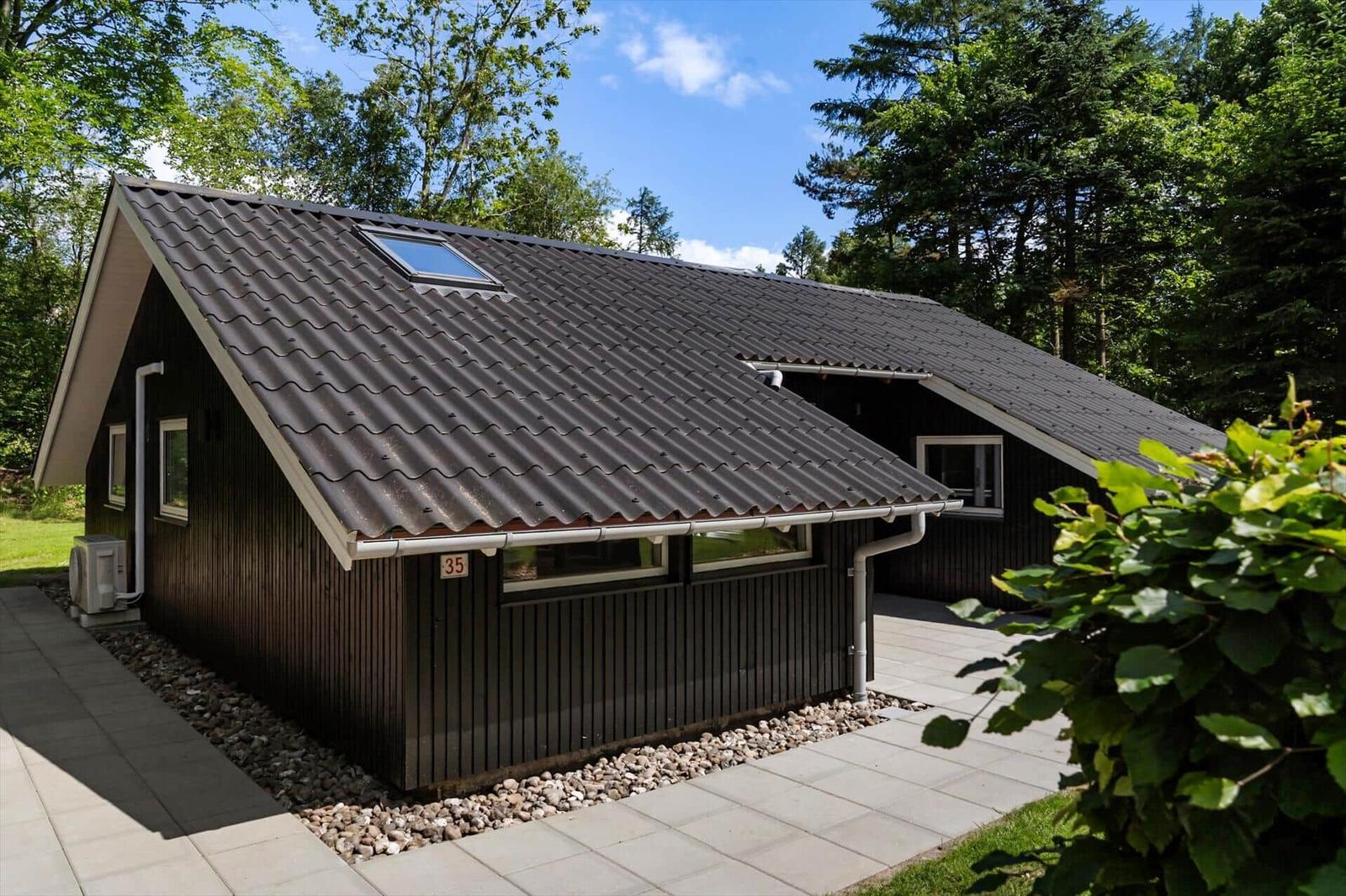 Holzhütte mit dunkler Fassade und Dachgauben im Wald.
