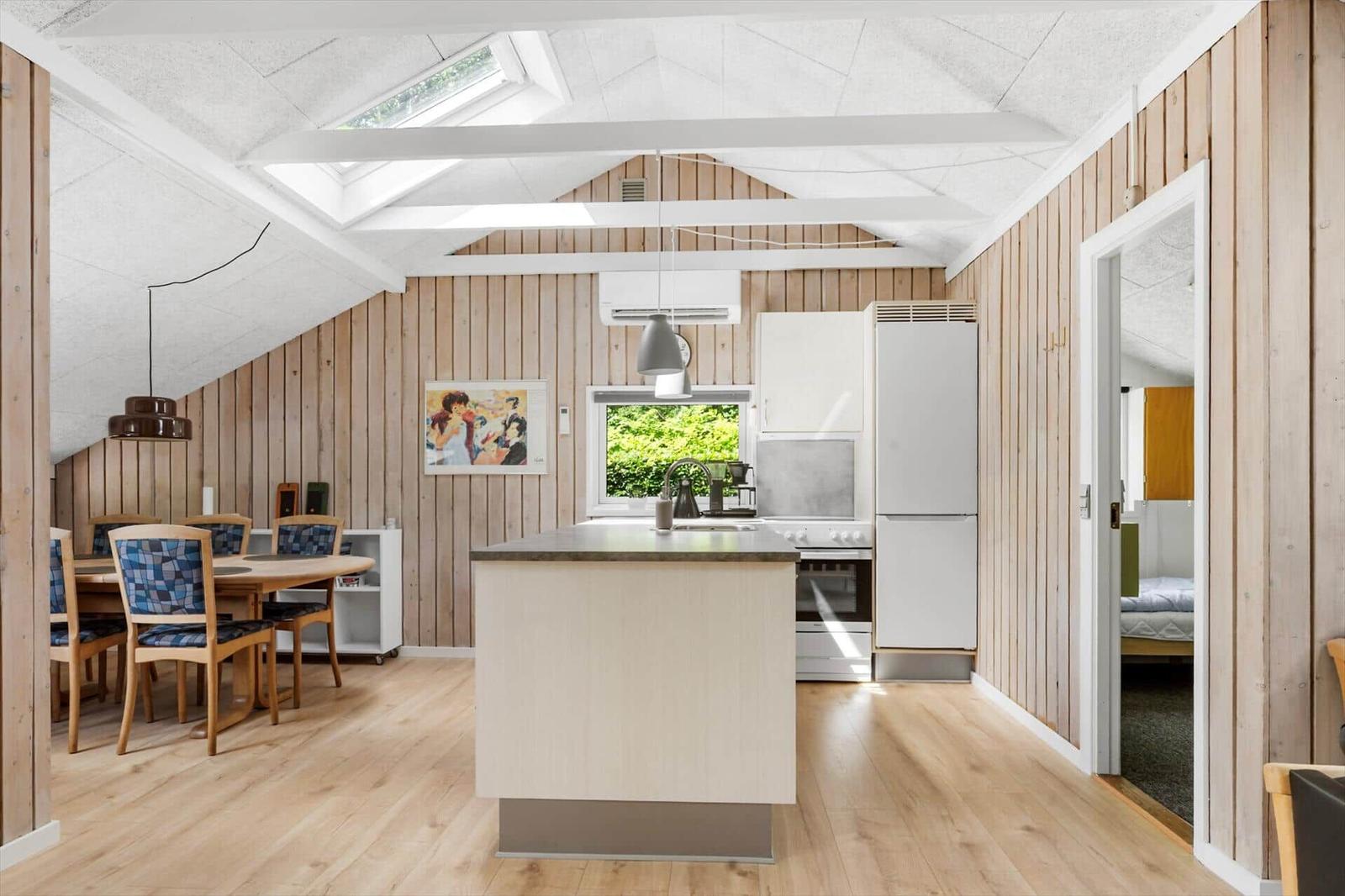 Küche mit Essbereich und Schlafzimmer. Holzwände und Dachfenster.