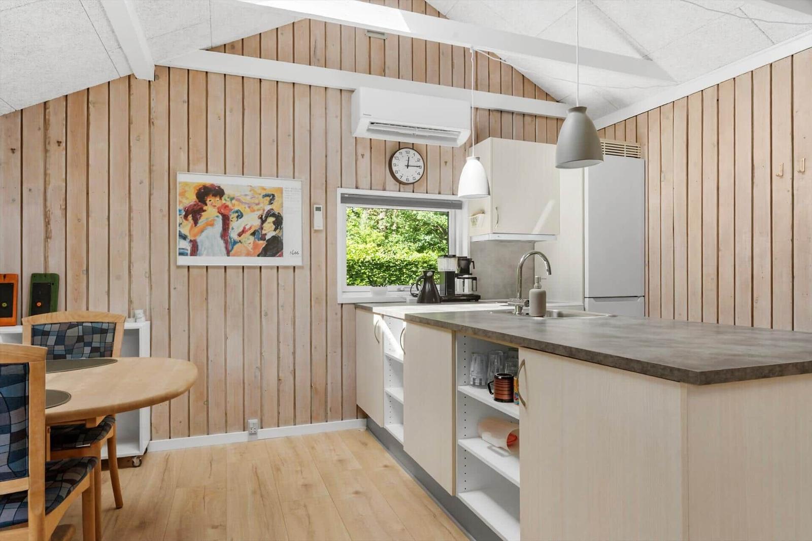 Küche mit Holzwand, Arbeitsplatte und Fenster mit Blick auf Grün