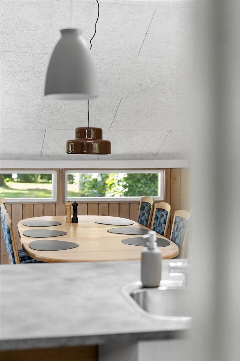 Rundes Esszimmer mit Holztisch, Stühlen und Fenstern. Hängelampe über dem Tisch.