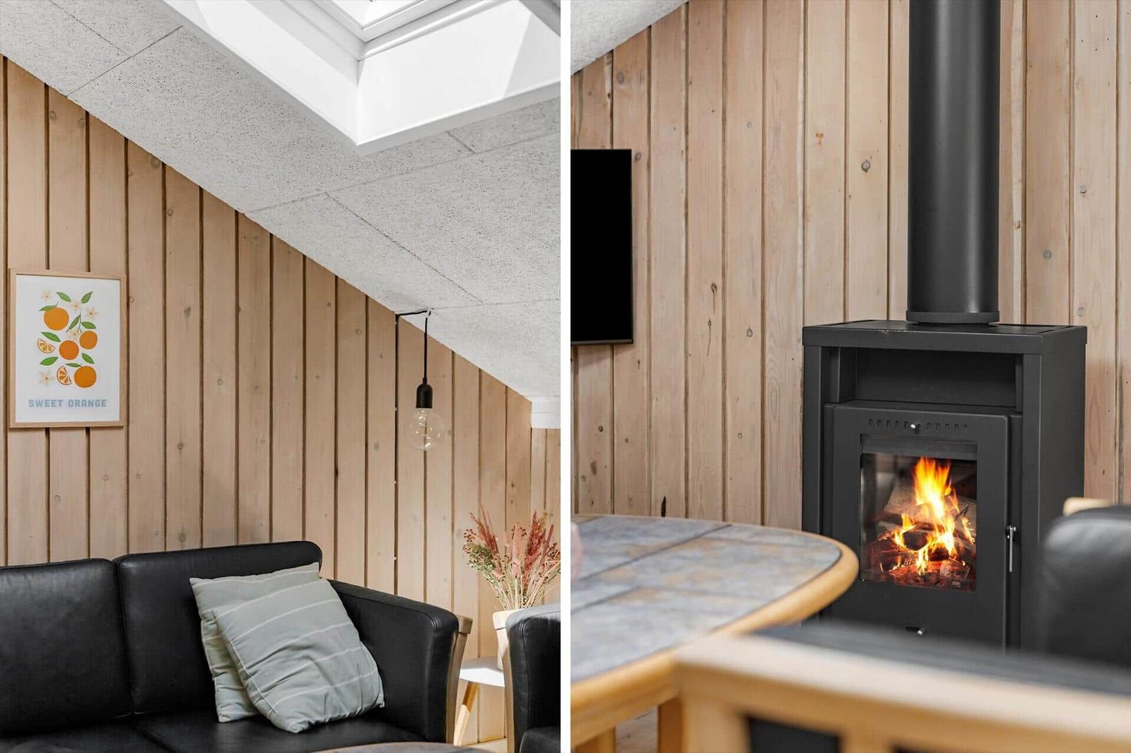 Wohnzimmer mit Holzwand, Sofa und Kaminofen. Deckenfenster und Wandbild sichtbar.