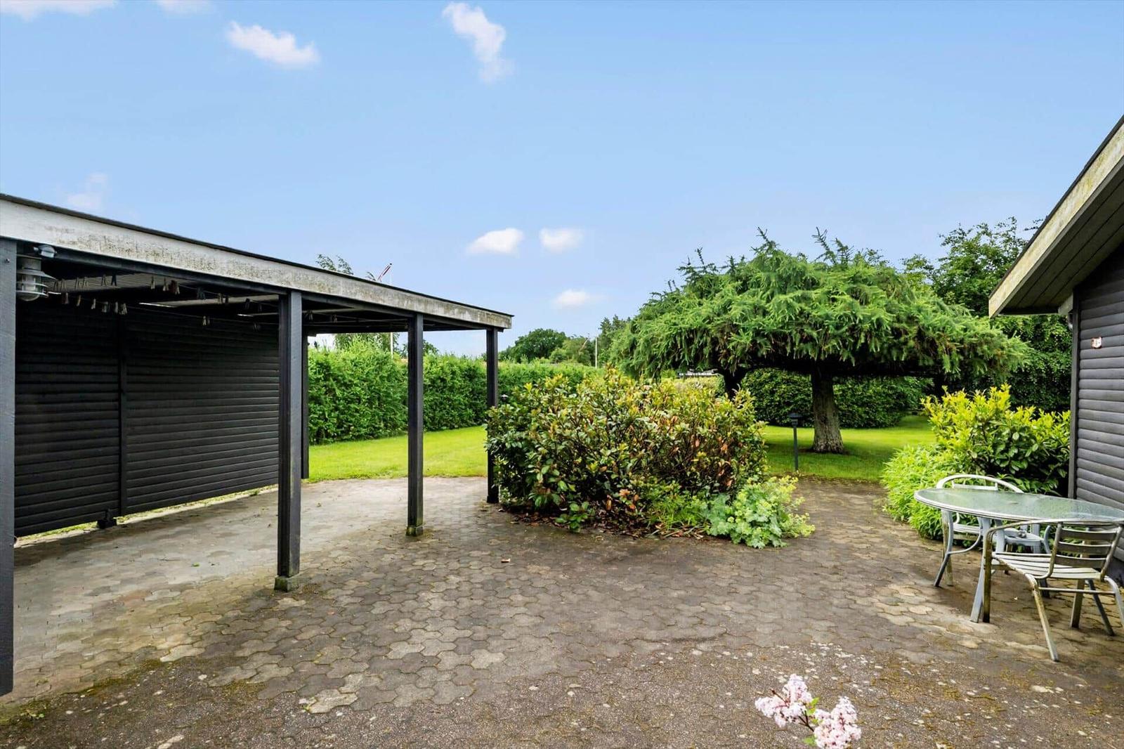 Hinterhof mit Pavillon, Tisch und Stühlen, Grünflächen und Bäumen.