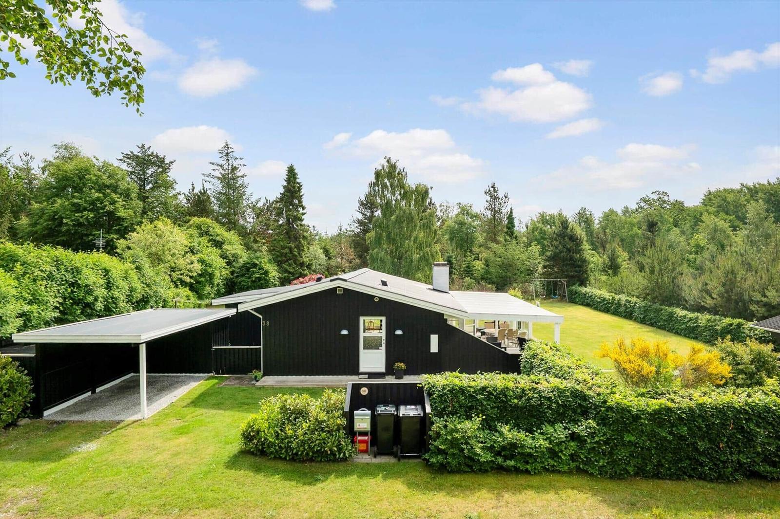 Schwarzes Haus mit Garage und Terrasse im grünen Garten