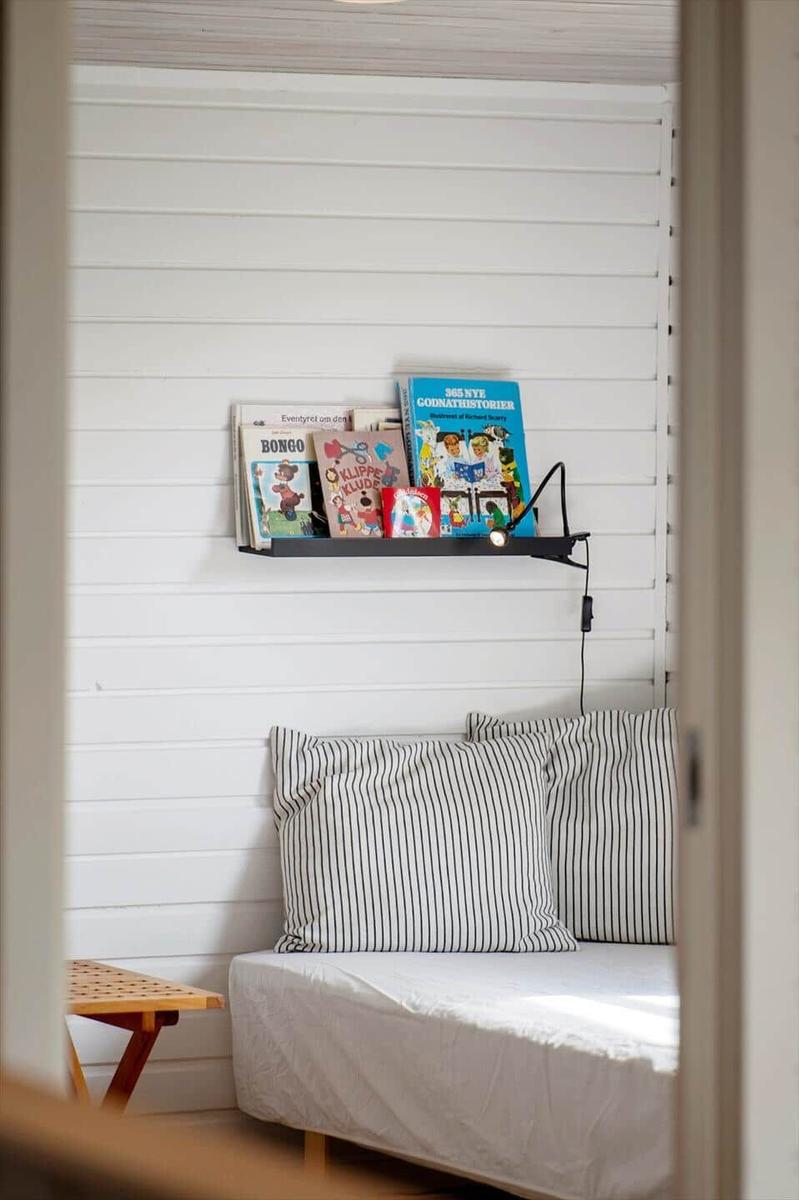 Ein Bett mit Streifenkissen und einem Bücherregal an der Wand.
