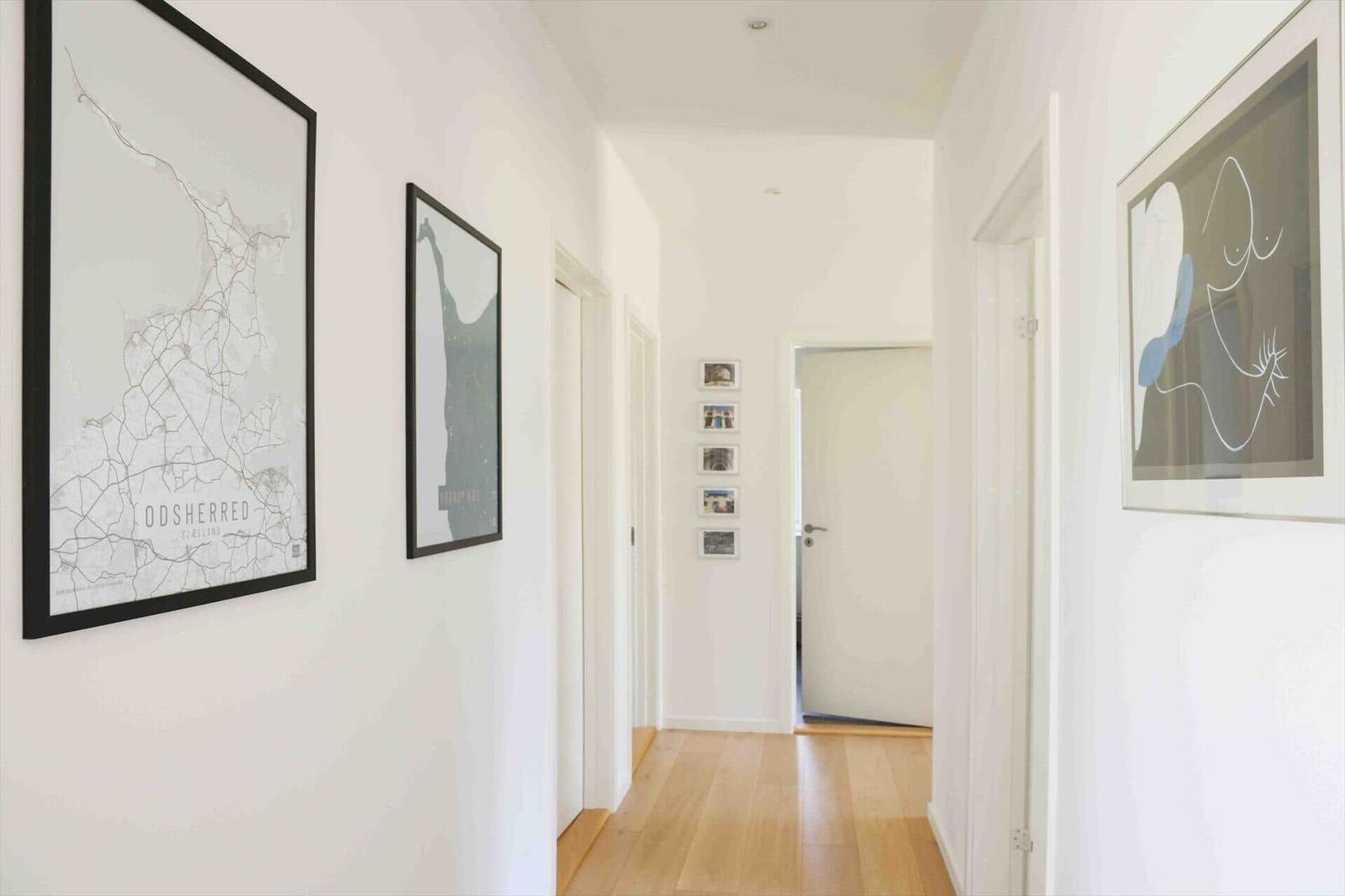 Hallway with wooden floor and wall art, including a map of Odsherred.