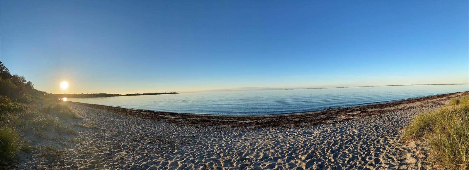 Beach with sand and calm water at sunrise.