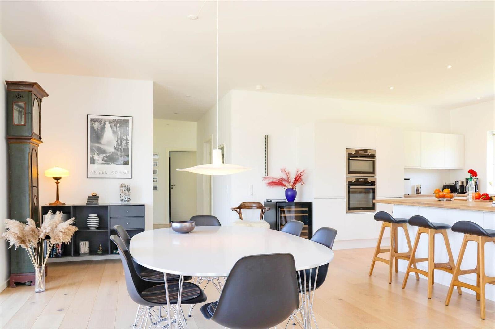 Dining area with round table and chairs, kitchen with countertop and bar stools.