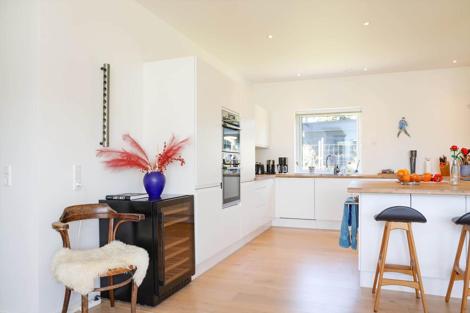 Modern kitchen with white cabinetry, wooden floor, and kitchen island with bar stools.