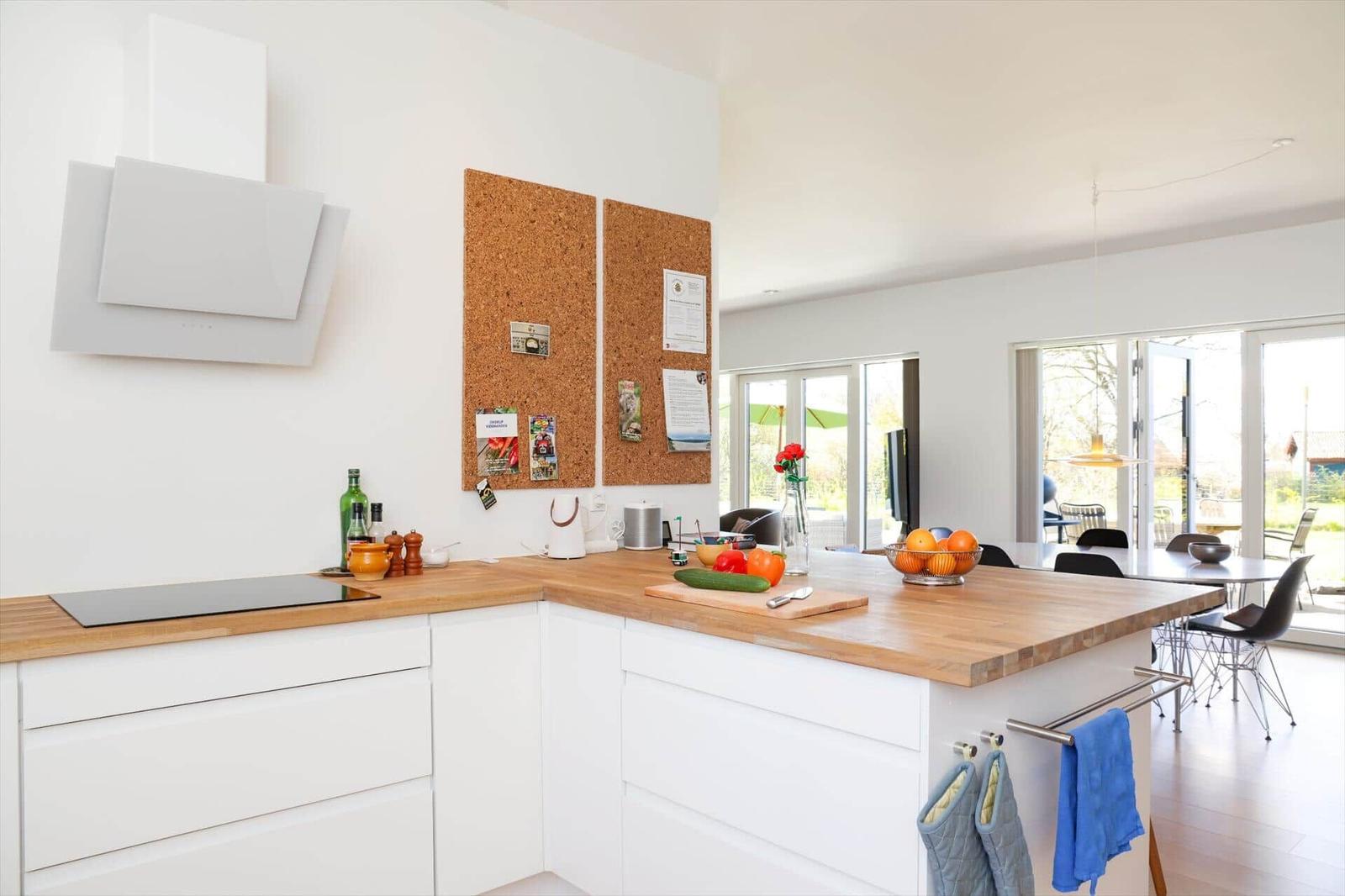 Modern kitchen with wooden surfaces and integrated kitchen island. View of dining area and garden.