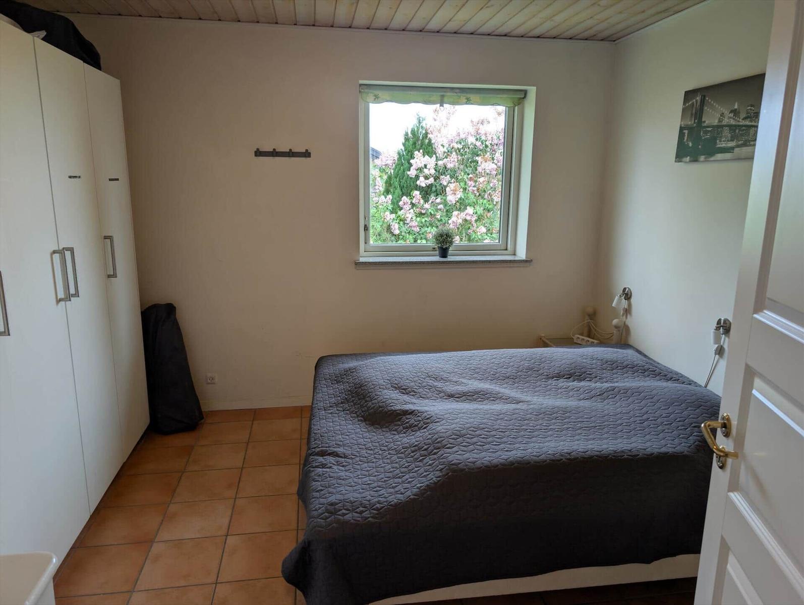 Bedroom with bed, wardrobe, and window with view of flowers.