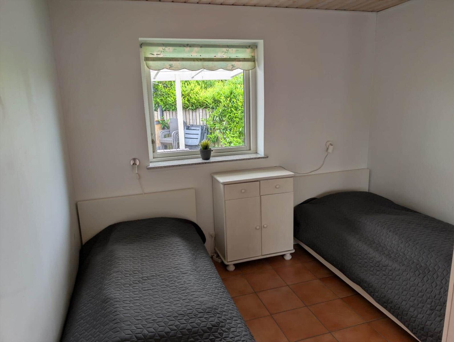 Two single beds, small cabinet, and window with garden view.