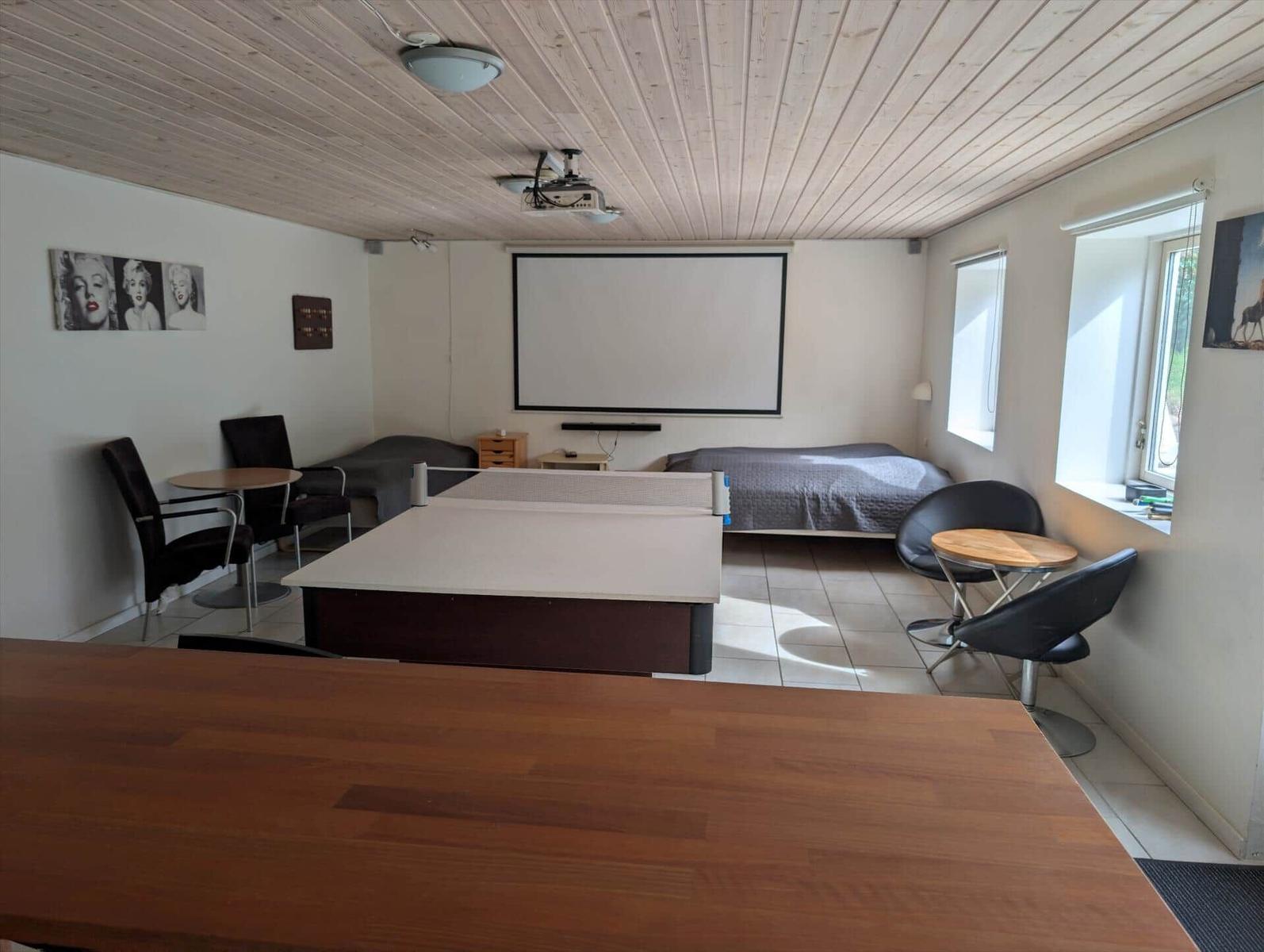 Room with ping pong table, bed, and projection screen on the wall.