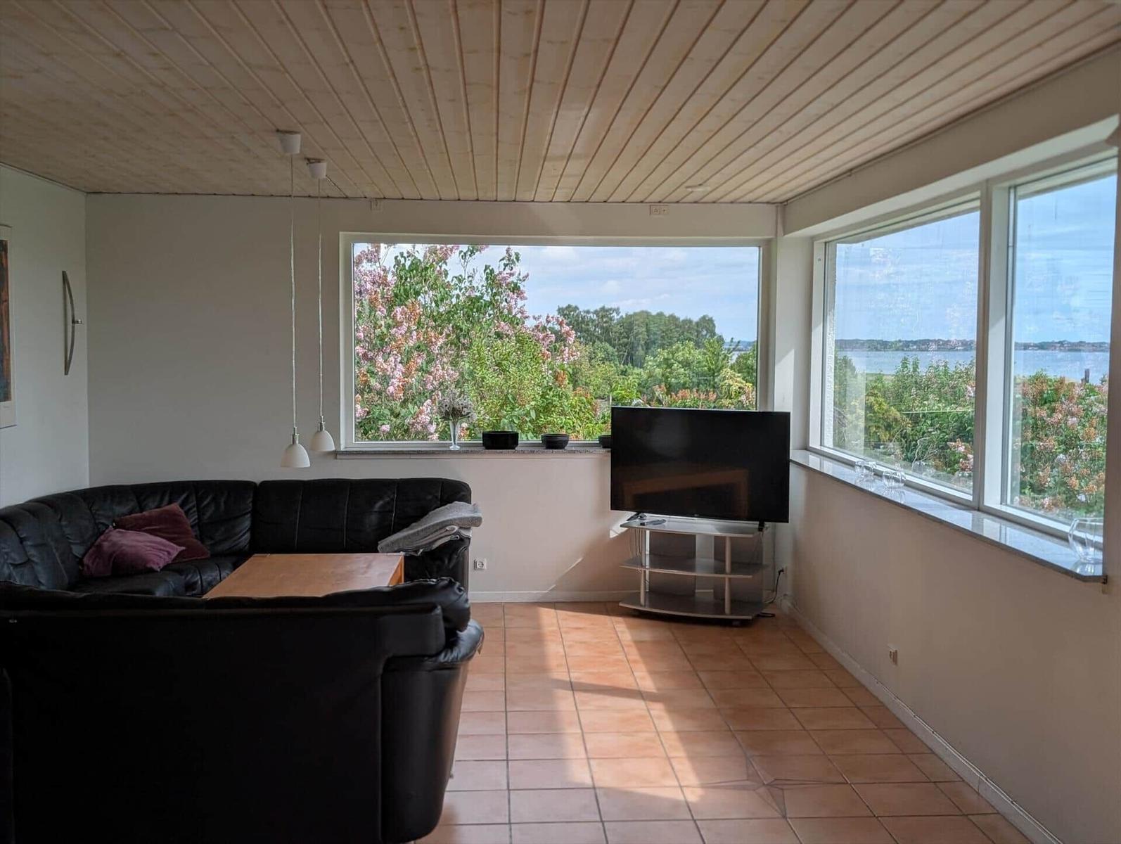 Living room with sofa, TV, and view of water and trees.