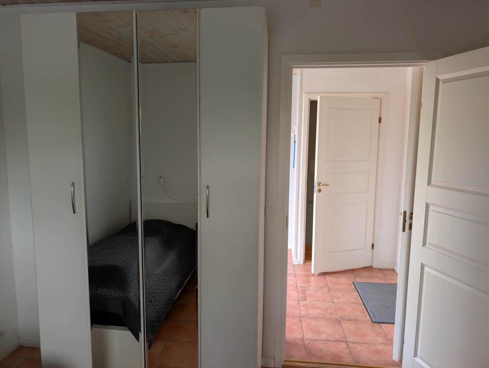 Bedroom with wardrobe and view into hallway with door.