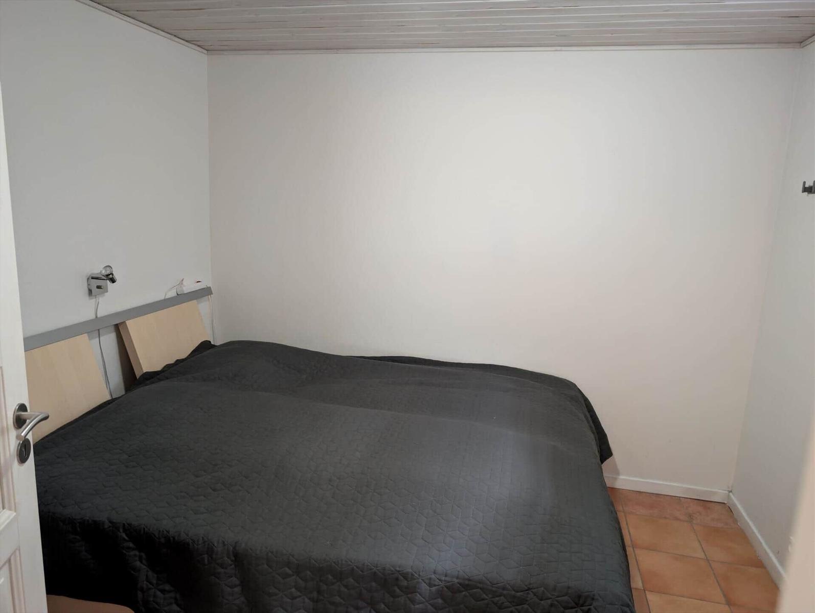 Bedroom with bed, wall lamp, and terracotta floor