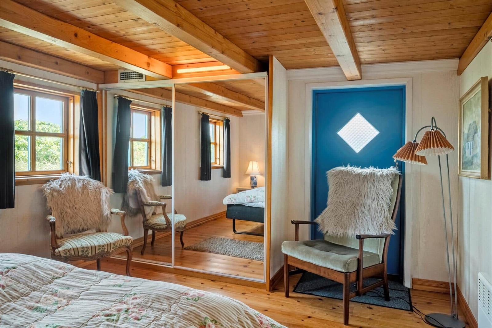 Schlafzimmer mit Holzboden, Spiegeltür und blauer Tür mit Fenster