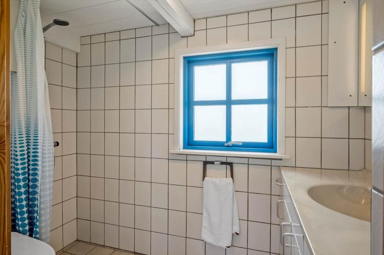 Badezimmer mit Dusche, Fenster mit blauem Rahmen und Waschbecken