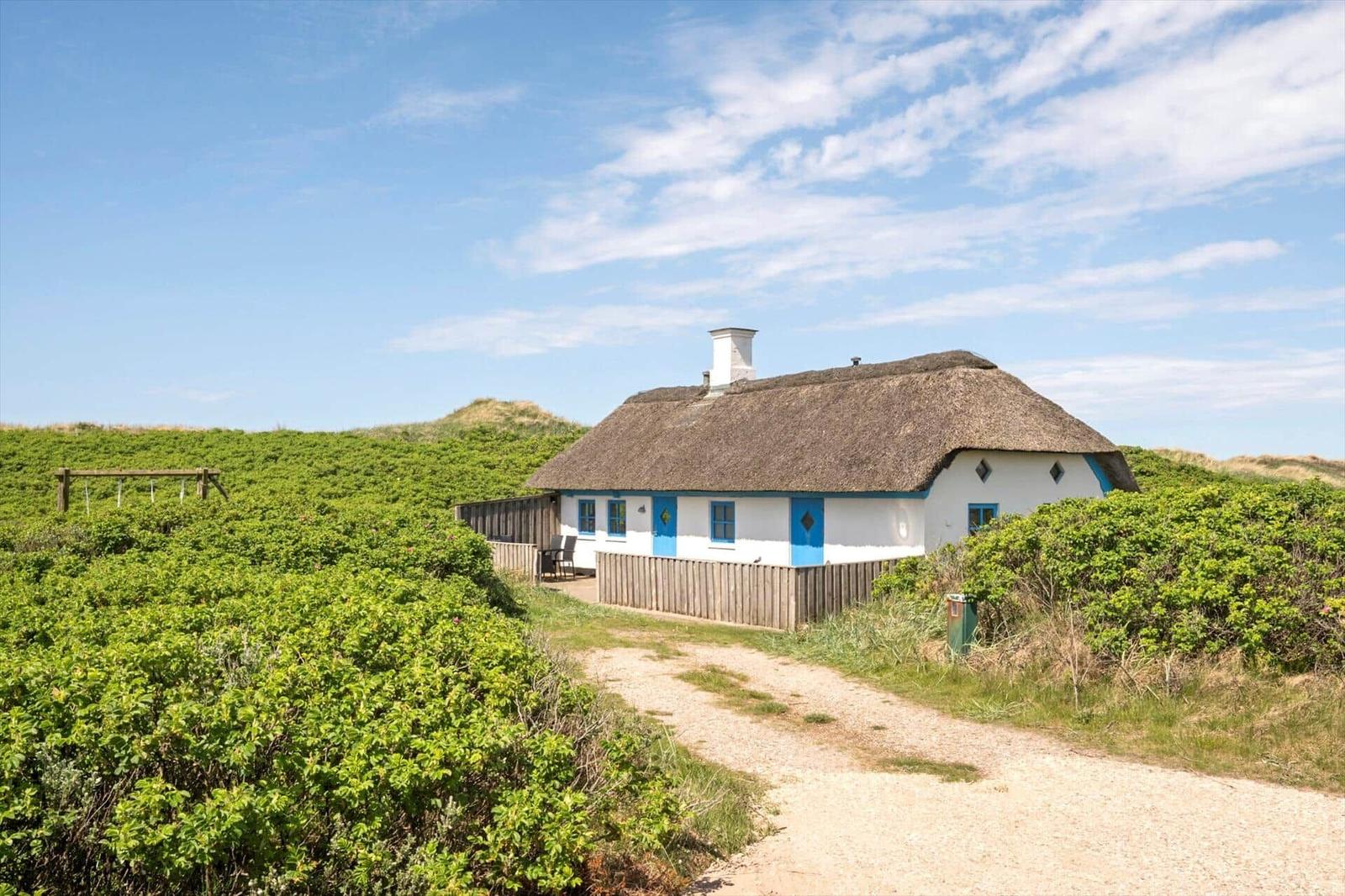 Hütte mit Strohdach und blauen Fenstern in grüner Umgebung