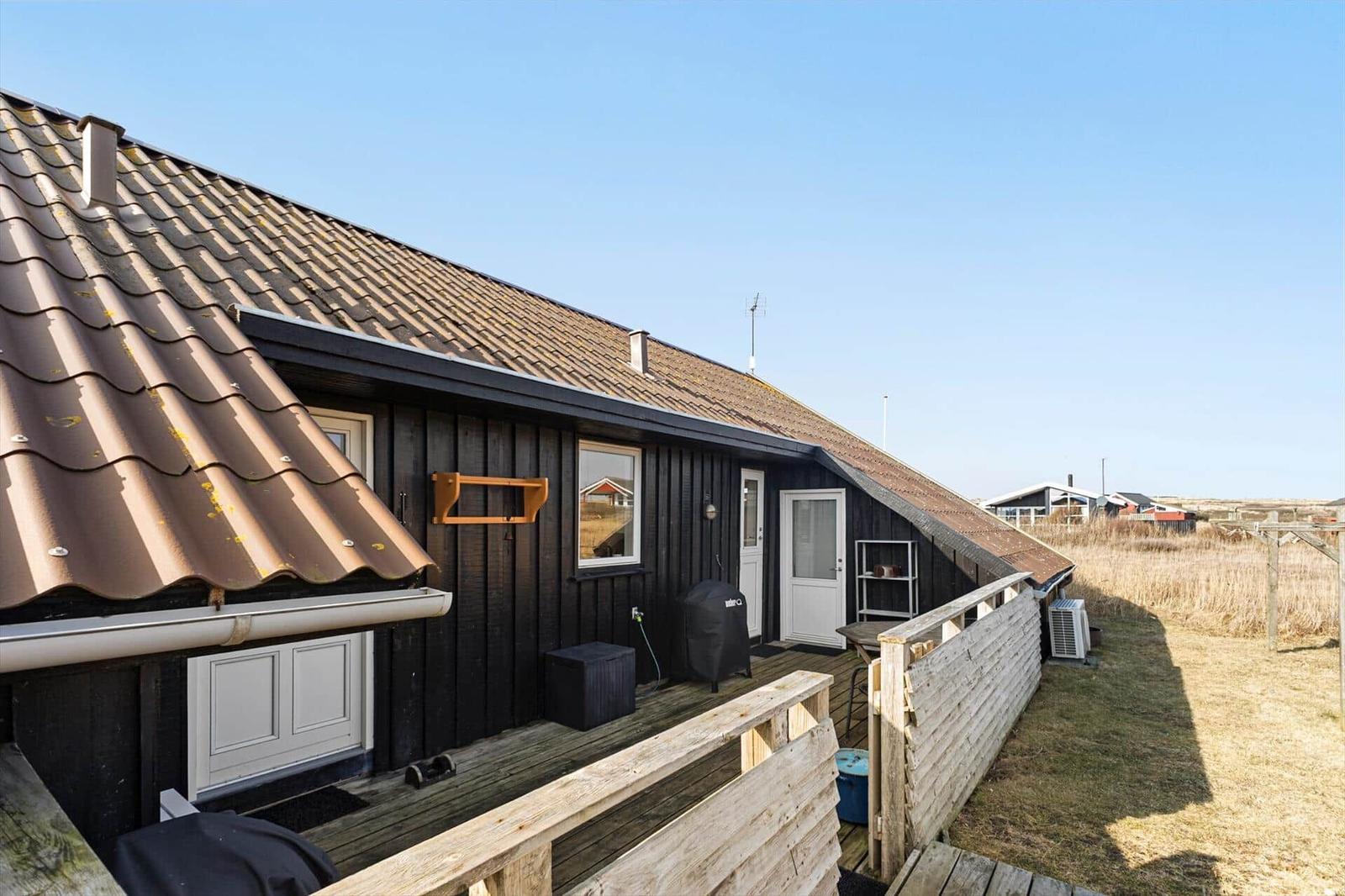 Holzhaus mit Dachterrasse und Grillplatz im Freien.