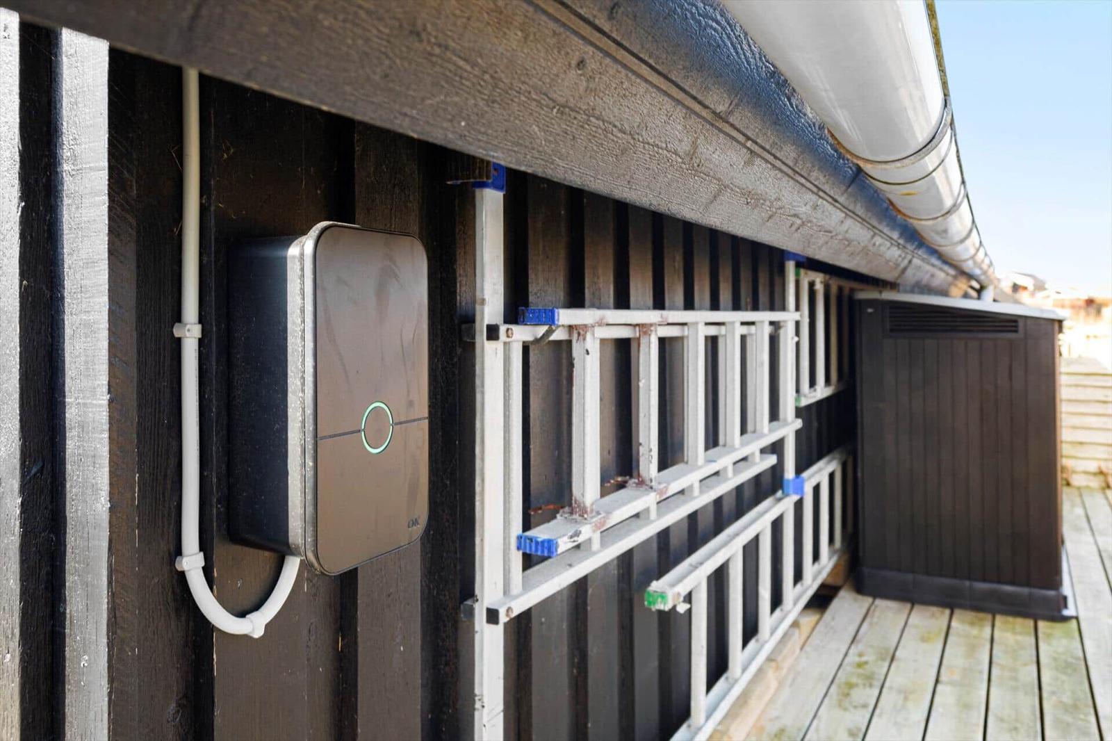 Außenansicht mit elektronischem Gerät an Wand, Leiter und Dachrinnen