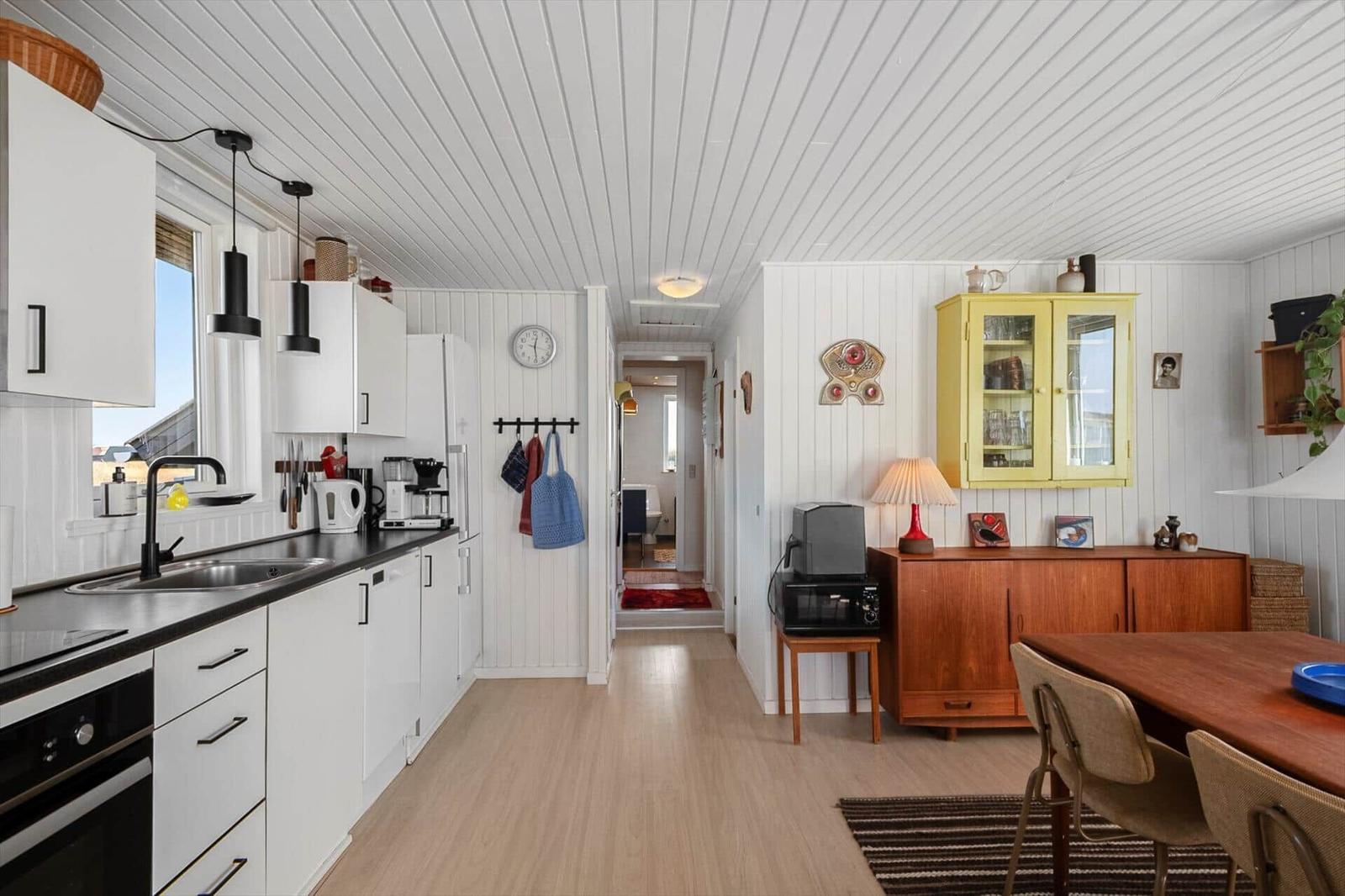 Küche mit Essbereich und Holzboden. Gelber Schrank und hölzerner Sideboard.