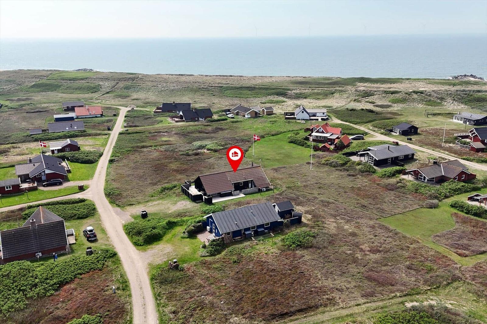 Haus mit rotem Dach in einer grünen Landschaft nahe dem Meer.