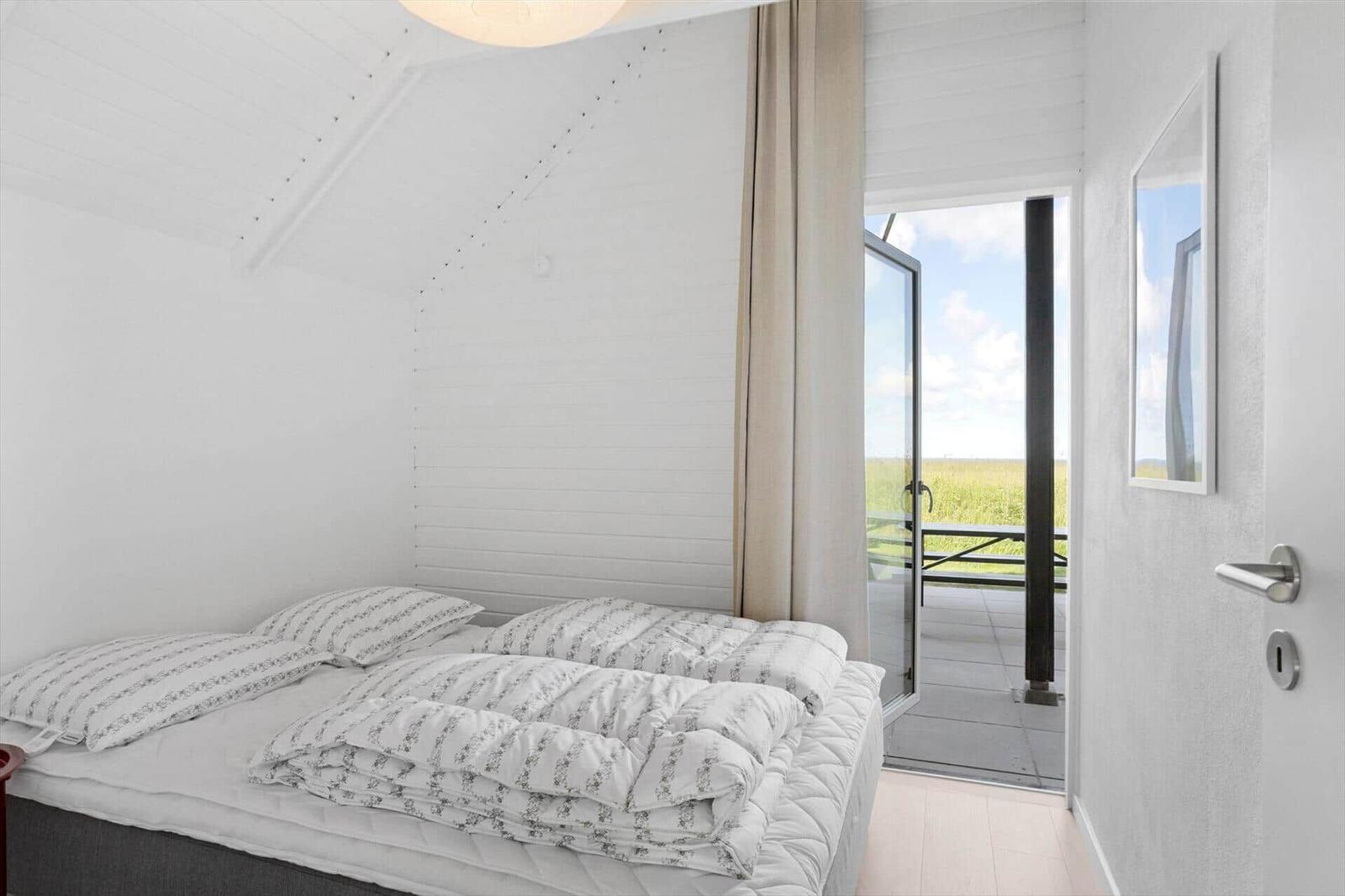 Bedroom with bed and balcony door to field
