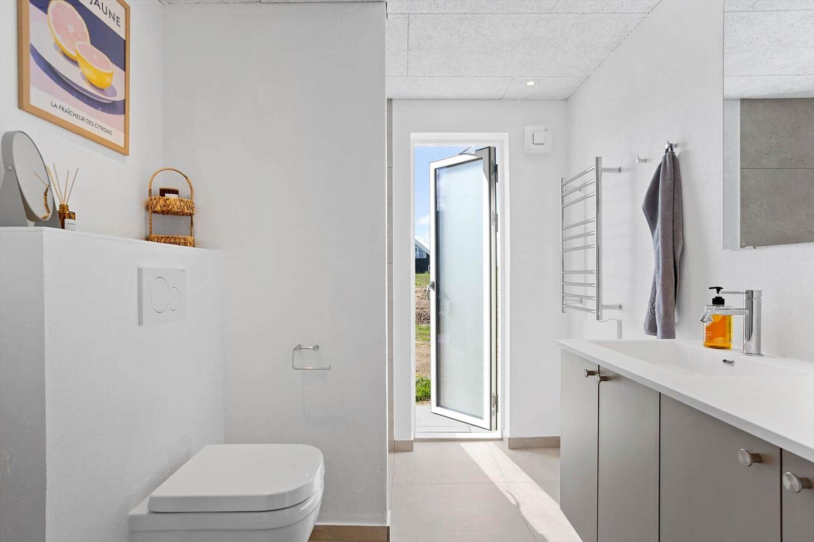 Bathroom with toilet, sink, and door to outdoor area.
