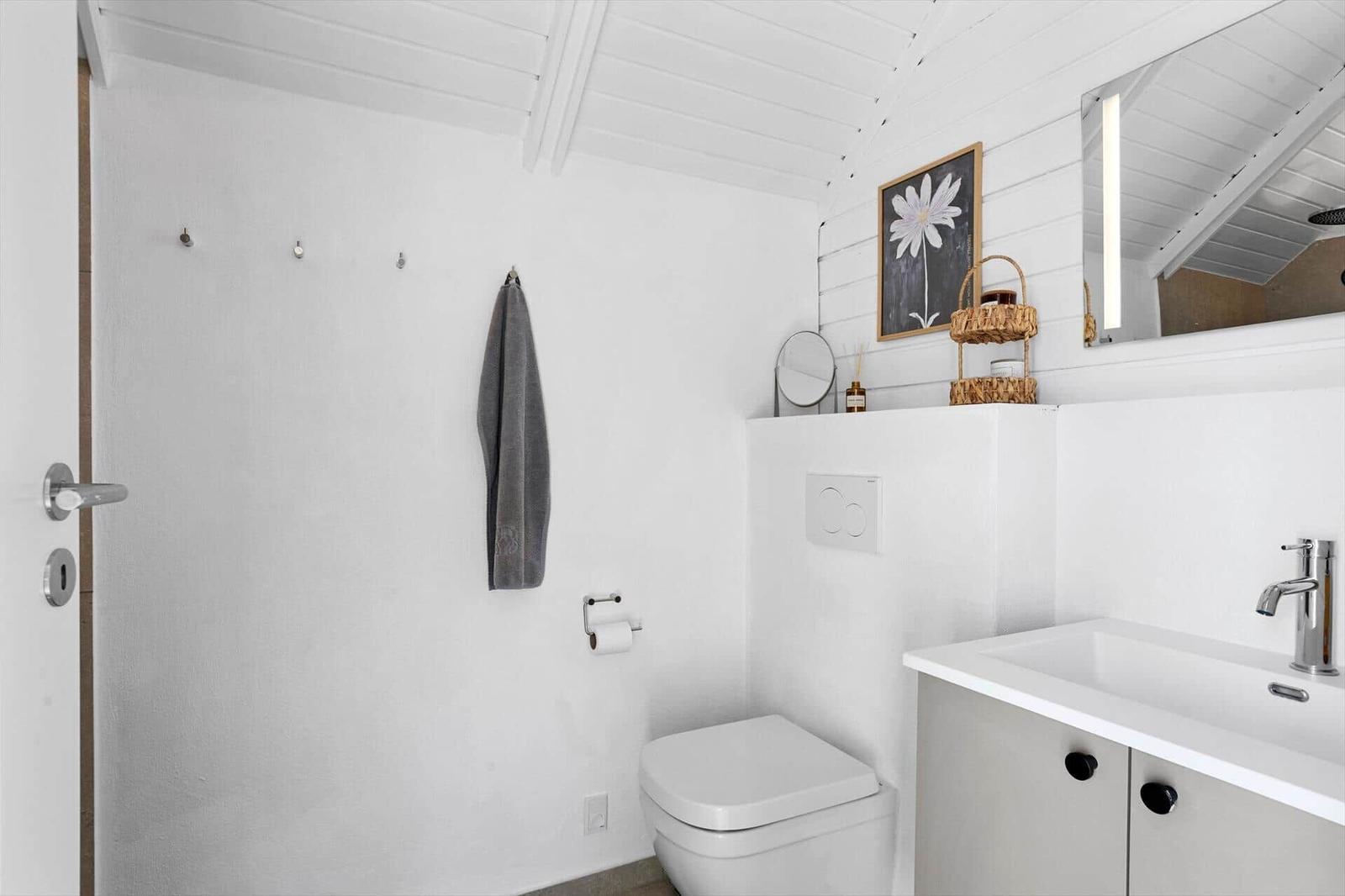 Bathroom with toilet, sink, and mirror on white wall.