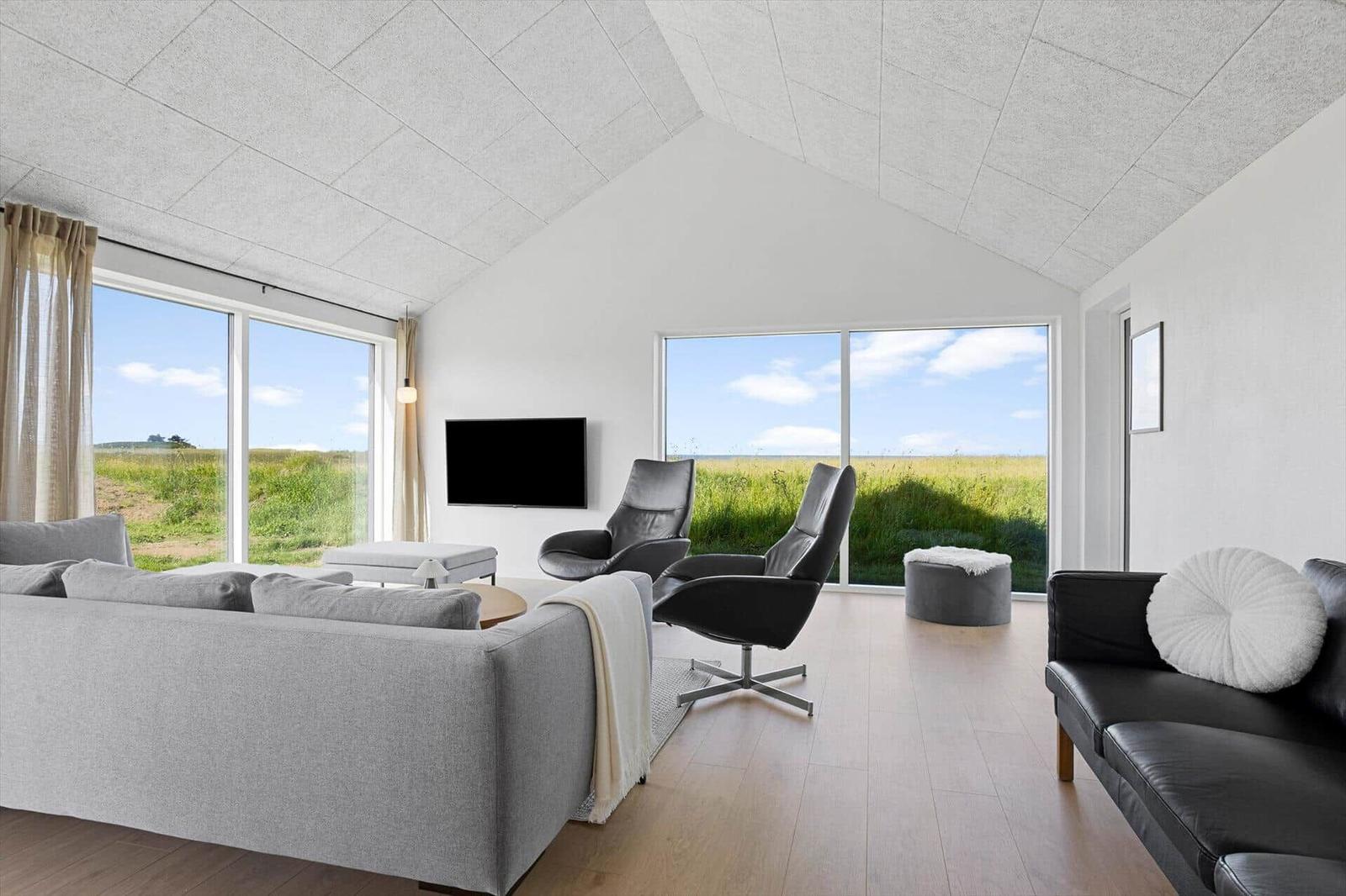 Living room with large window view of fields and TV mounted on wall.