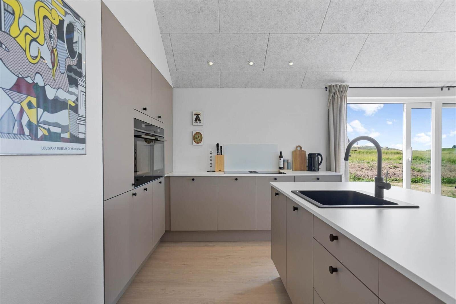 Modern kitchen with integrated oven and view of a green landscape.