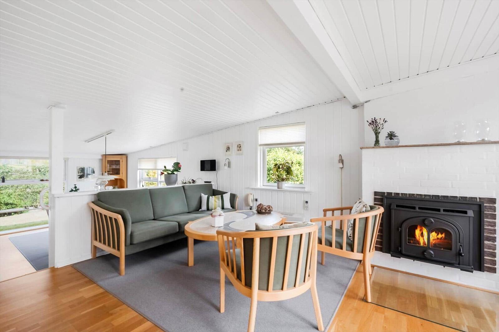 Wohnzimmer mit Sofa, Sesseln, Kamin und Fenstern.