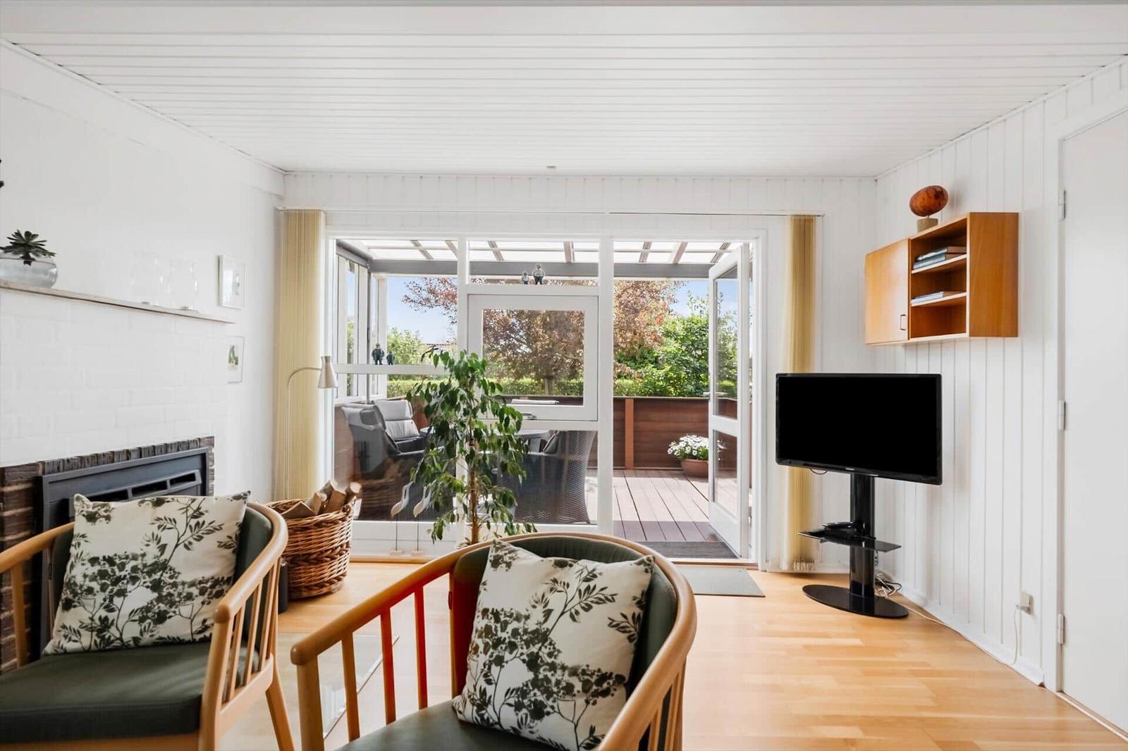 Wohnzimmer mit Kamin, zwei Sesseln und Blick auf Terrasse.