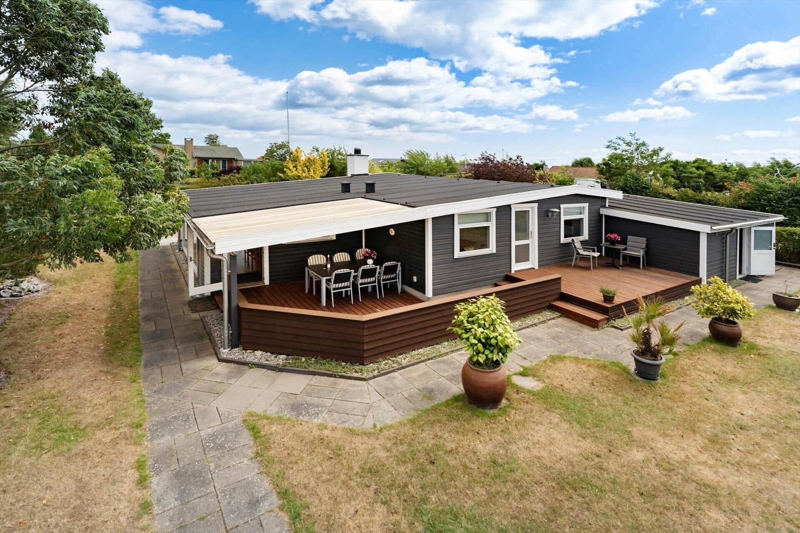 Ein modernes Haus mit Terrasse und Garten. Außentisch und Stühle sind vorhanden.