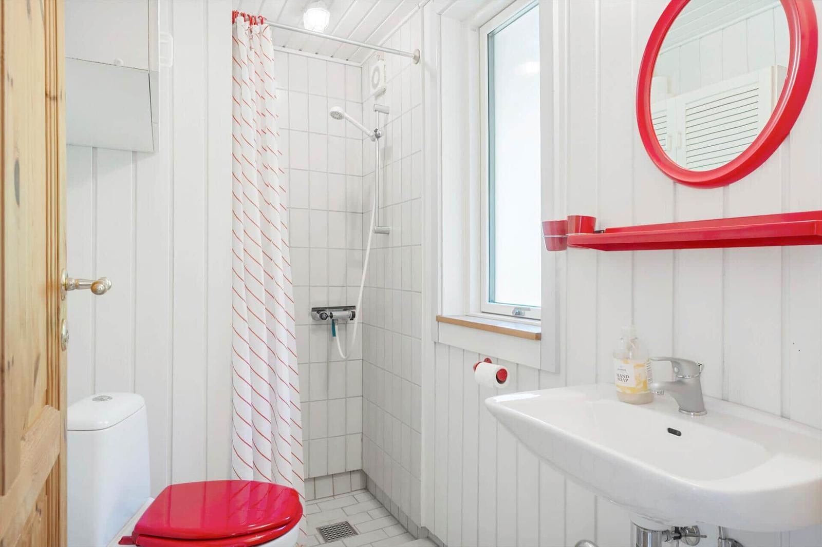 Bathroom with shower, toilet, and sink with red mirror and towel holder.
